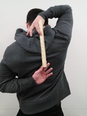person holding a ruler behind back with own hands from bottom of neck to middle of back