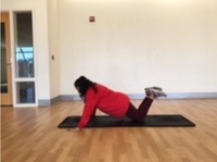 person in the modified push up position with knees on floor and arms extended shoulder-width apart with back in line (diagonal to knees)