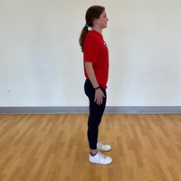 side profile of person standing straight with arms at side with shoulders rotated back