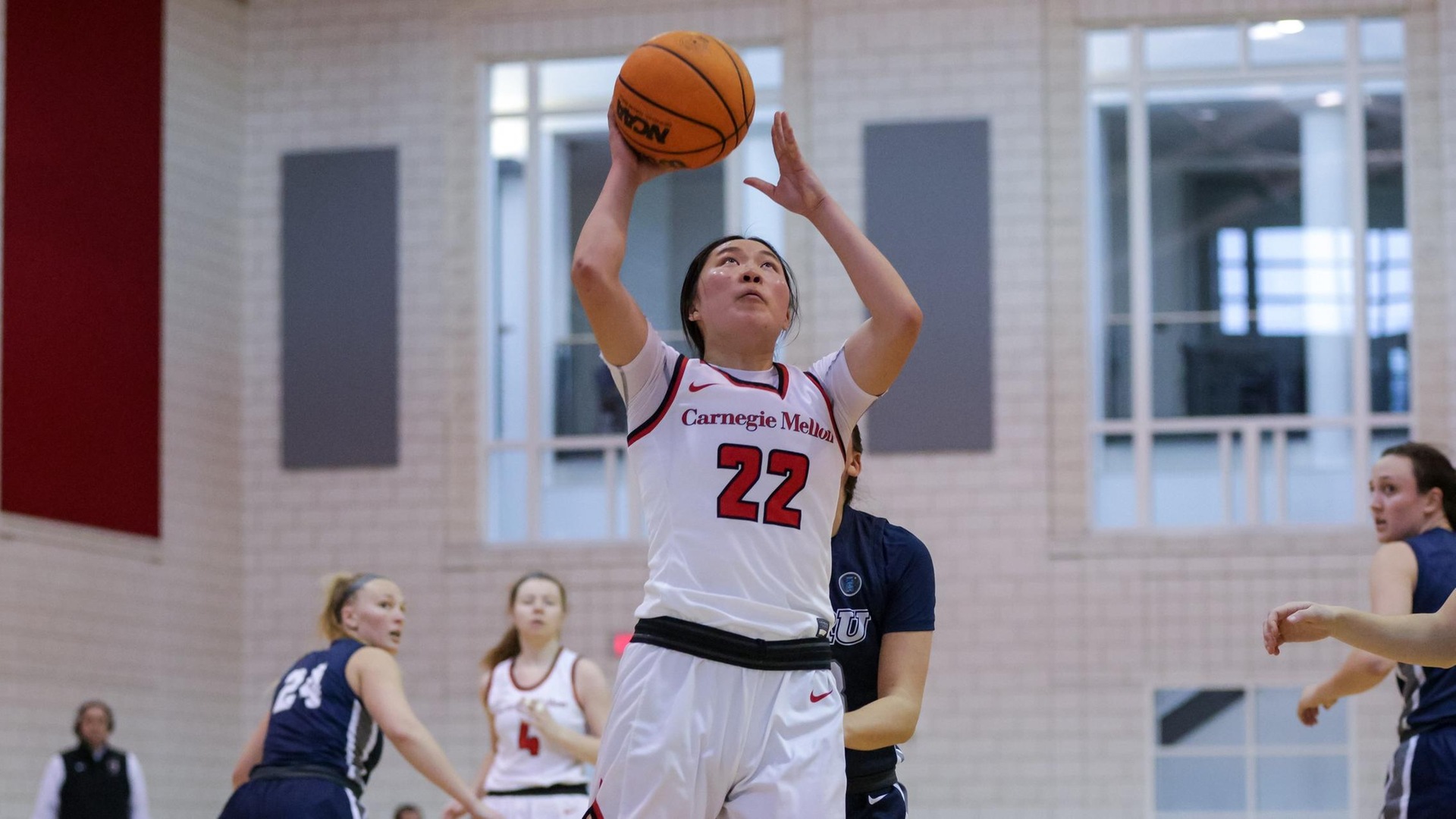 women's basketball player wearing a white uniform taking a right-handed shot