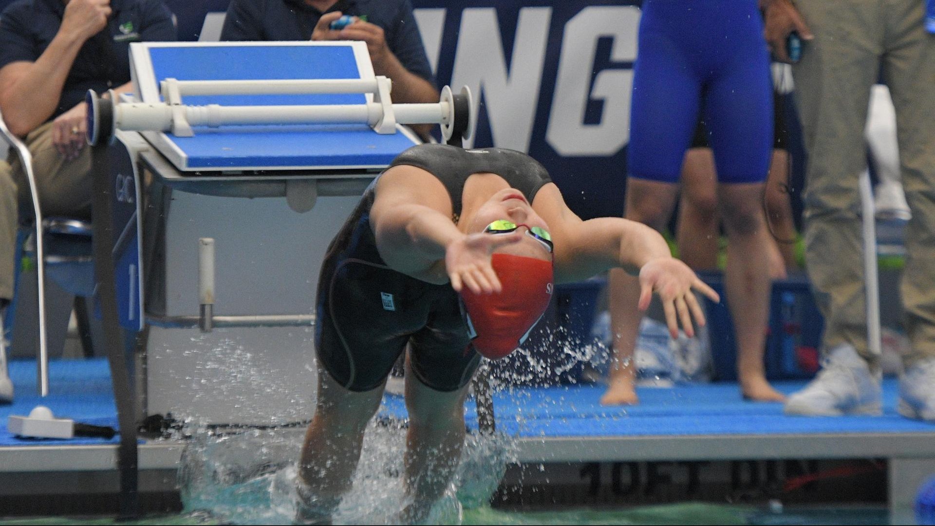 women's swimmer leaping off wall to start the backstroke
