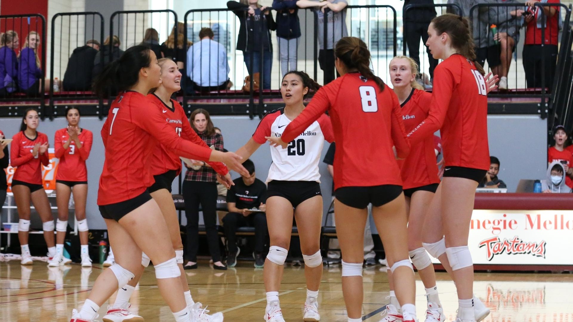 women's volleyball players smiling in a huddle