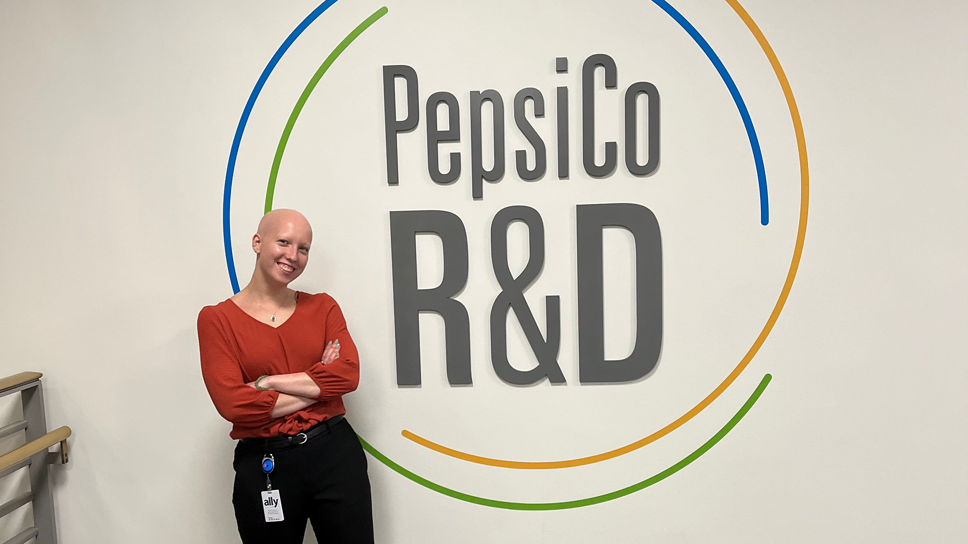 woman standing in front of a wall with text reading PepsiCo R&D