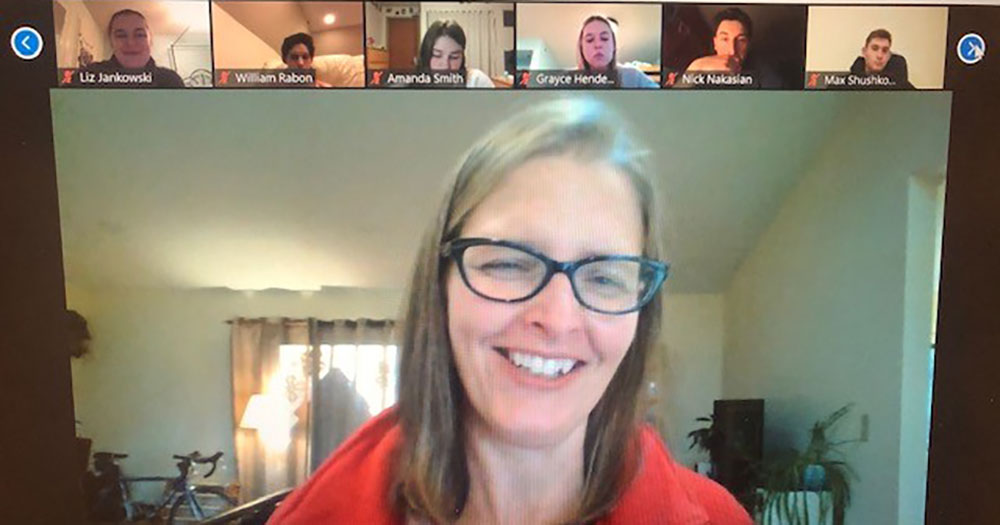Zoom meeting with six participants to the top and the main speaker, a woman with glasses, in the middle center