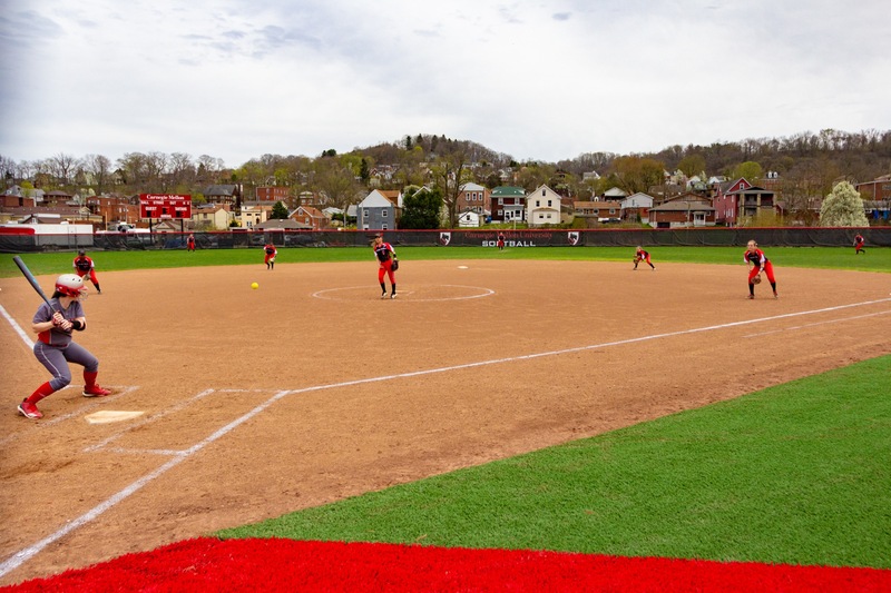 softball field with players in fielding positions and a batter at the plate