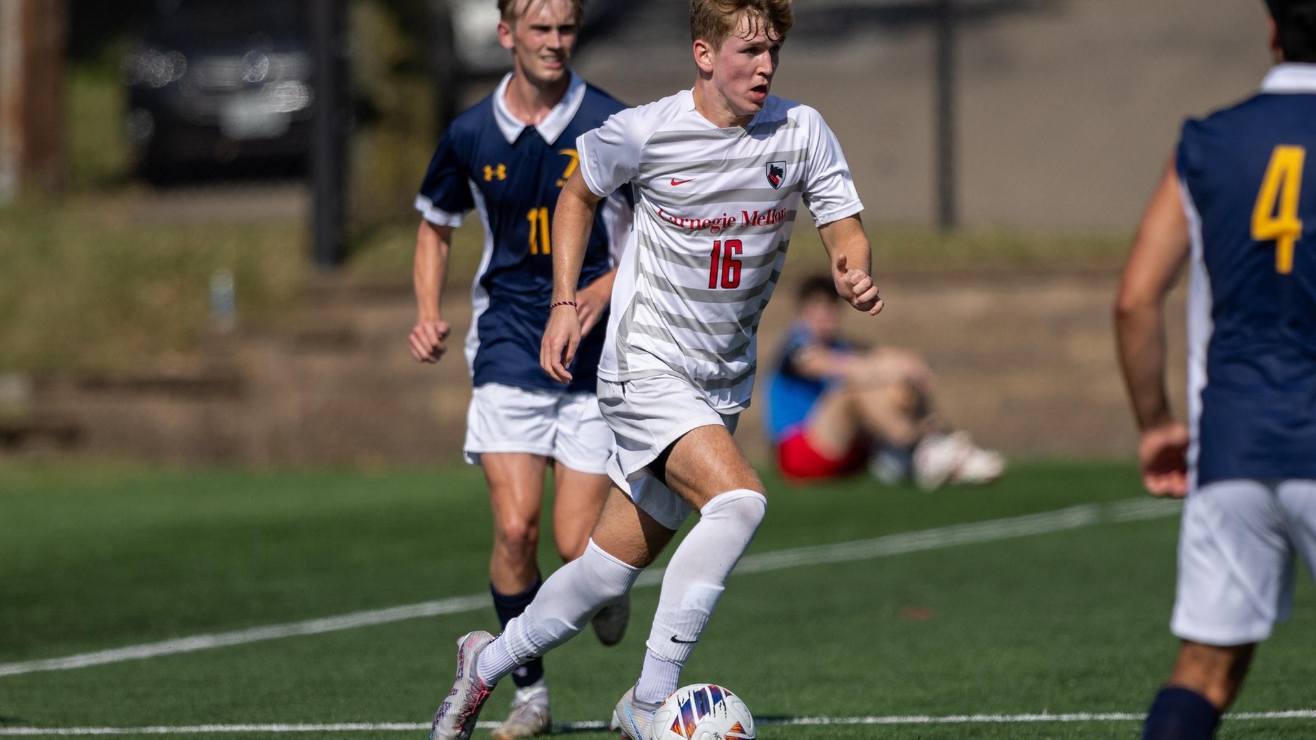 men's soccer player wearing a white uniform has ball at right foot 