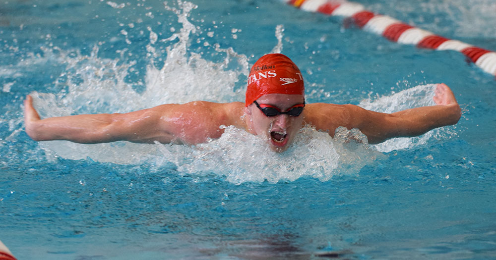 male swimming the butterfly with a red cap