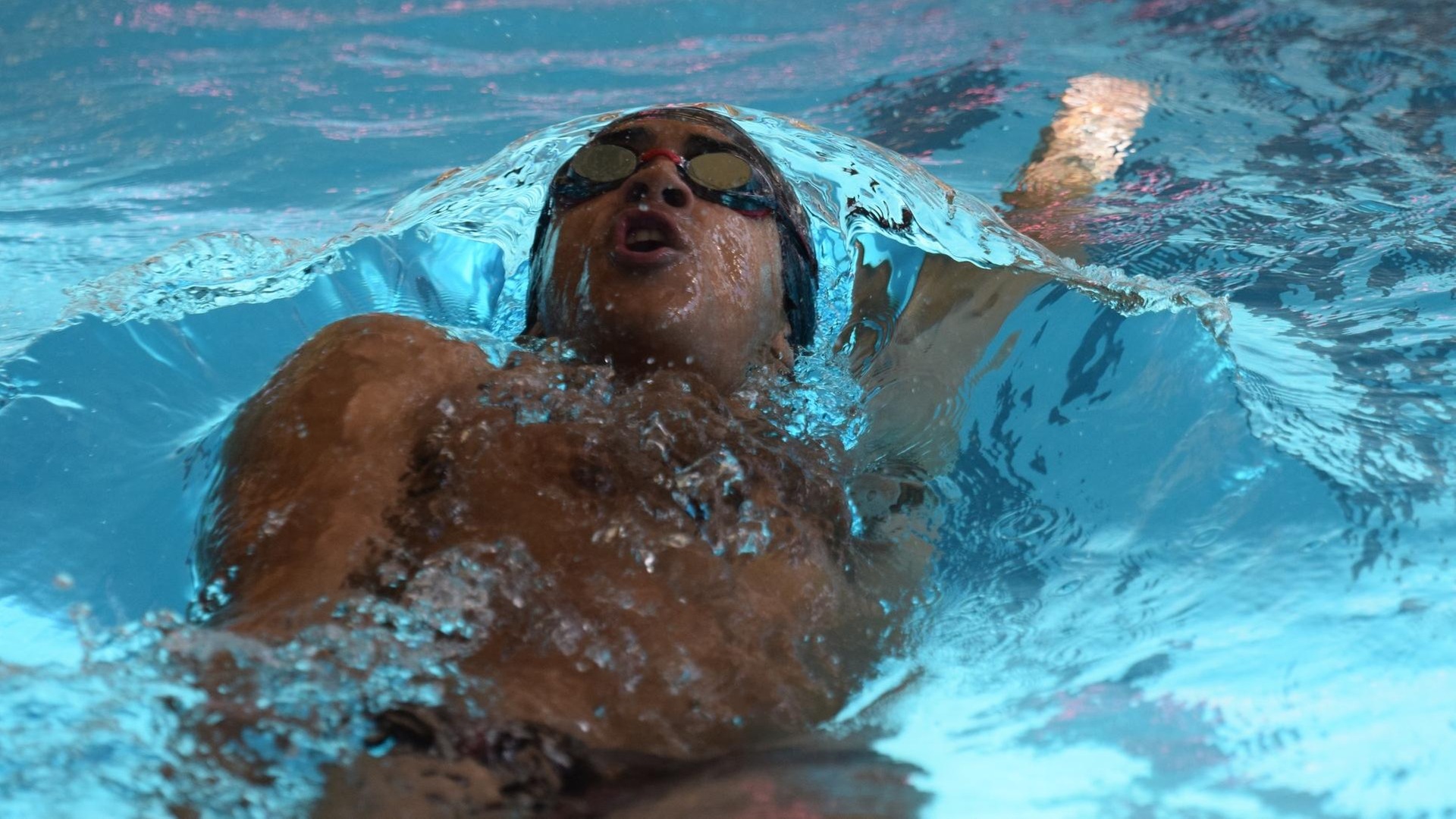 men's swimmer breaching water doing the backstroke
