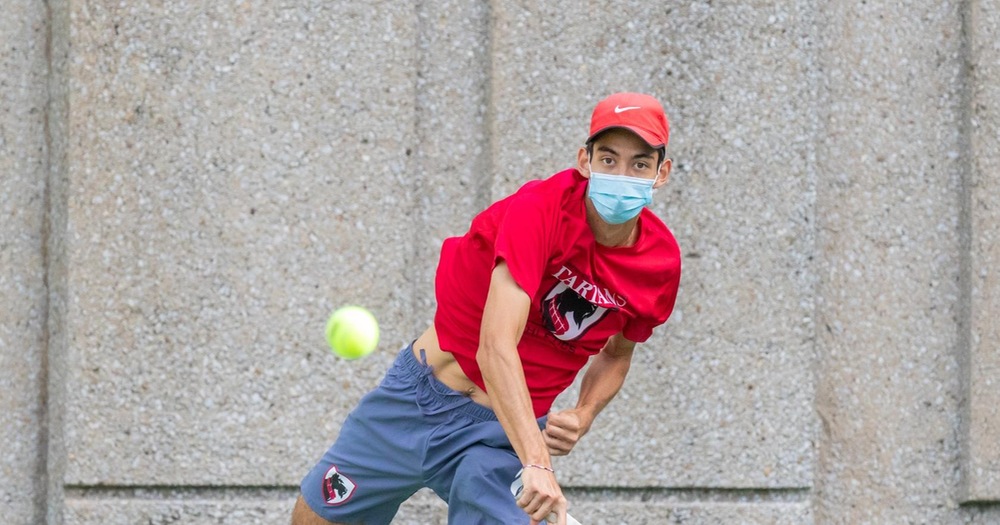 men's tennis player wearing red shirt returning a shot