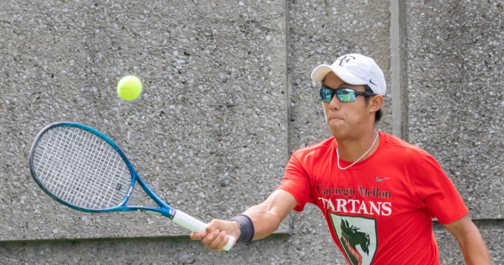 men's tennis player wearing red shirt, white hat, and sunglasses swinging at a ball with their right hand