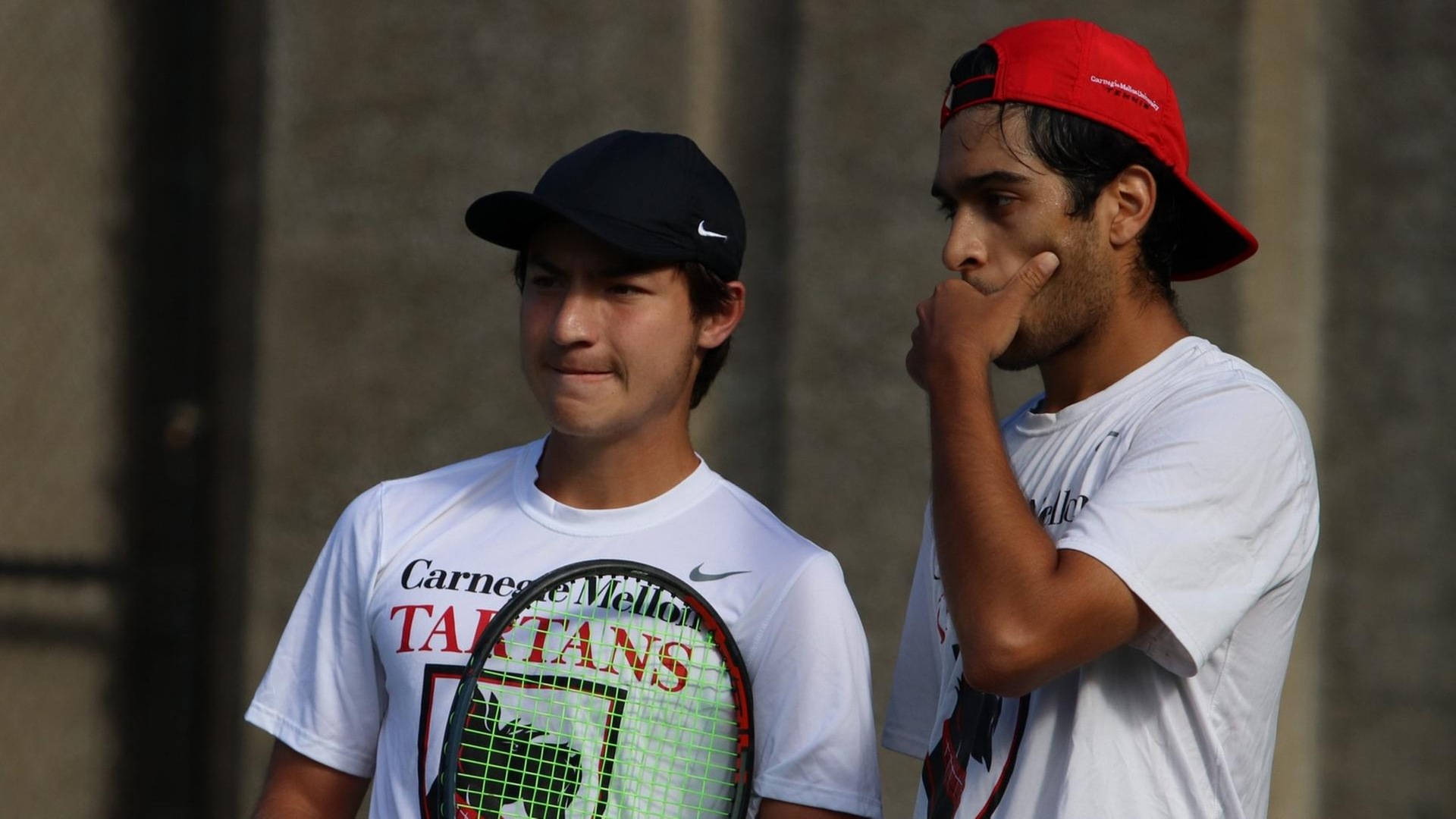 two men's tennis players wearing white shirts talking before a play