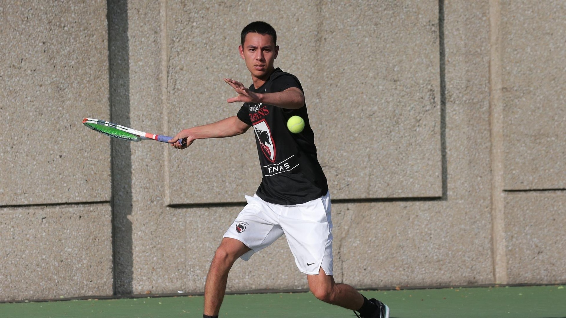 men's tennis player wearing a black shirt and white shorts swings racquet at ball