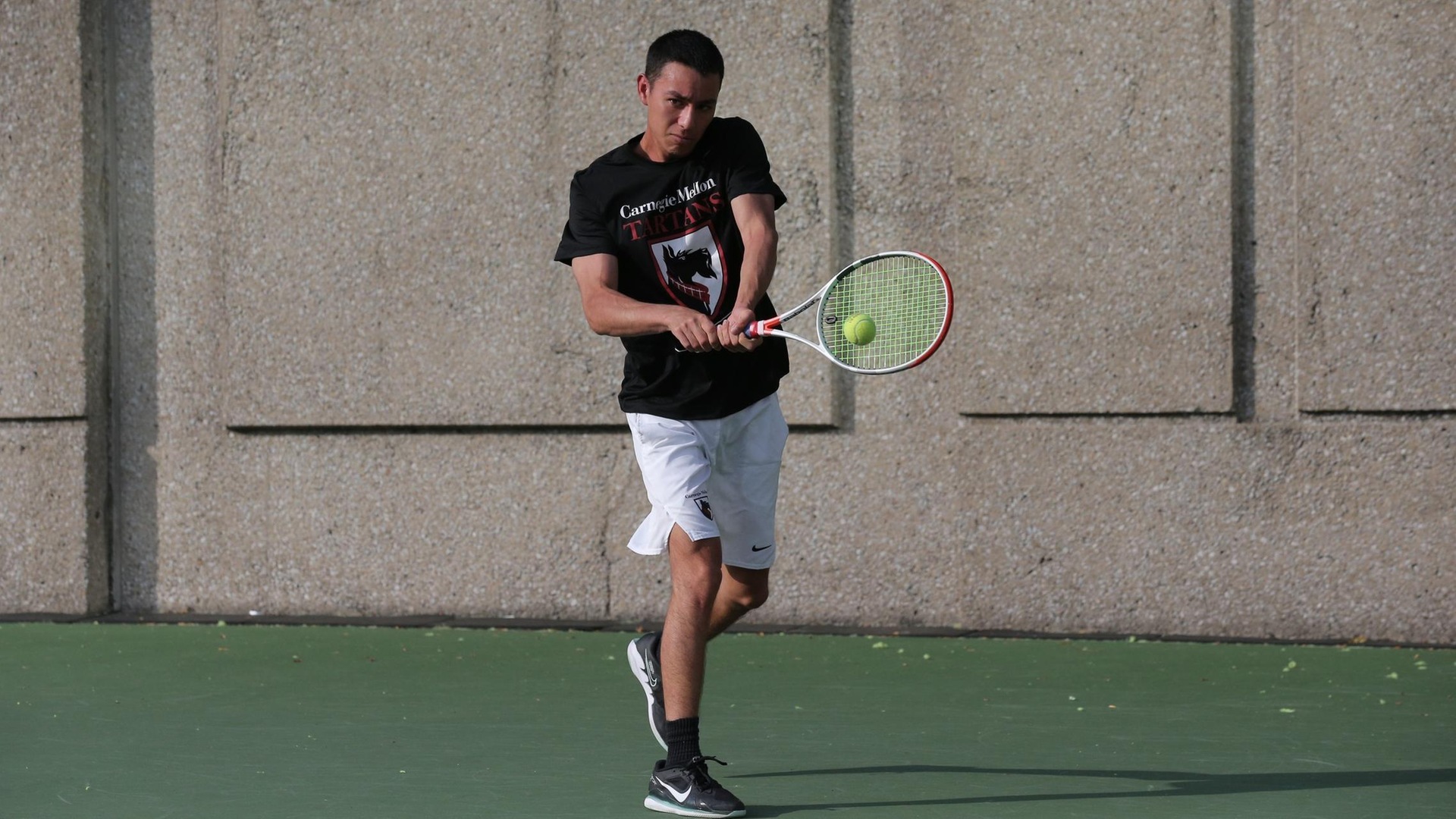 men's tennis player wearing a black shirt and white shorts swinging a racquet with two hands