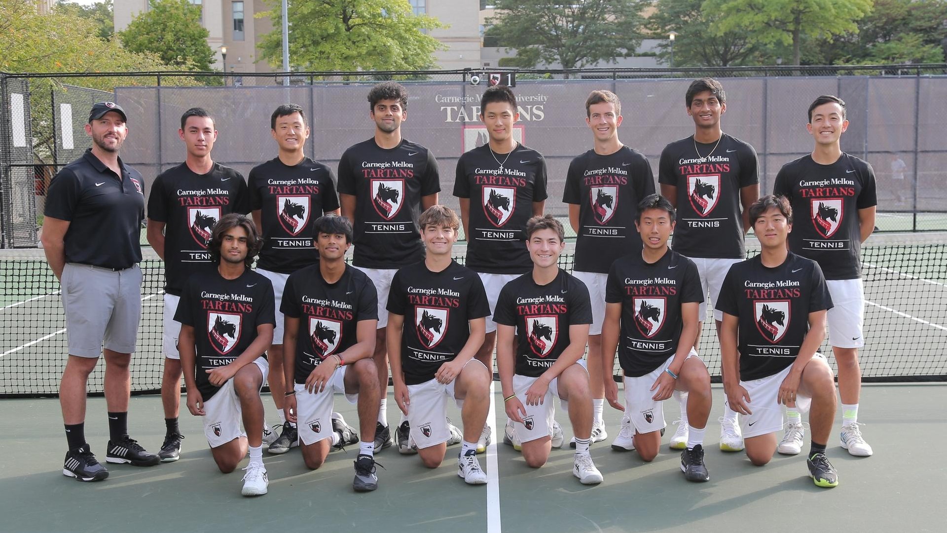 men's tennis team photo with players wearing black shirts and white shorts with one row kneeling and one row standing