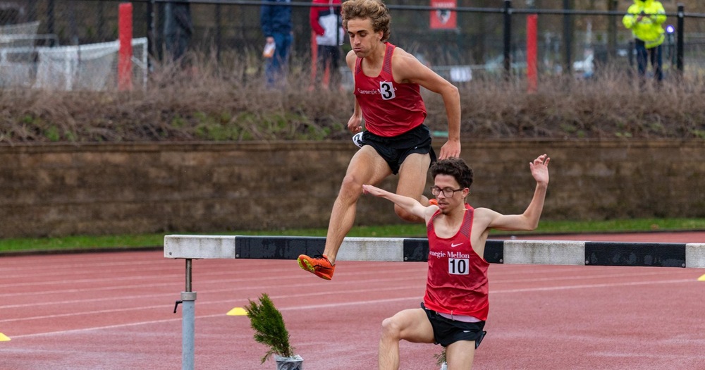 two men's track athletes crossing the barrier for the steeplechase