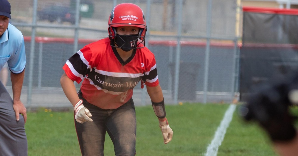 softball player leading off from third base