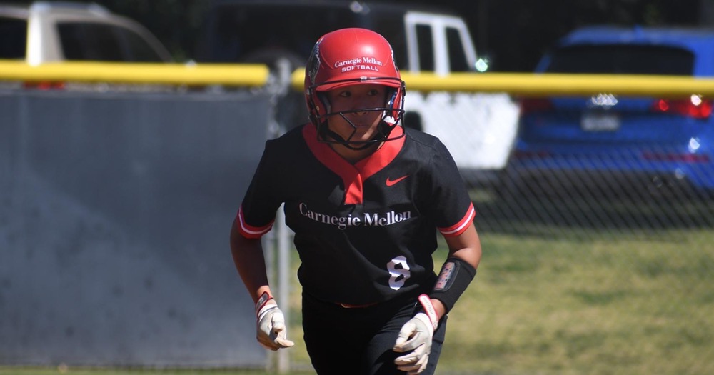 women's softball player in black shirt and black pants with red helmet running the bases
