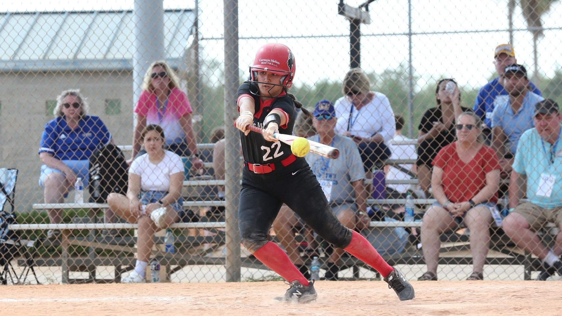 left-handed softball batter reaching bat out to hit ball