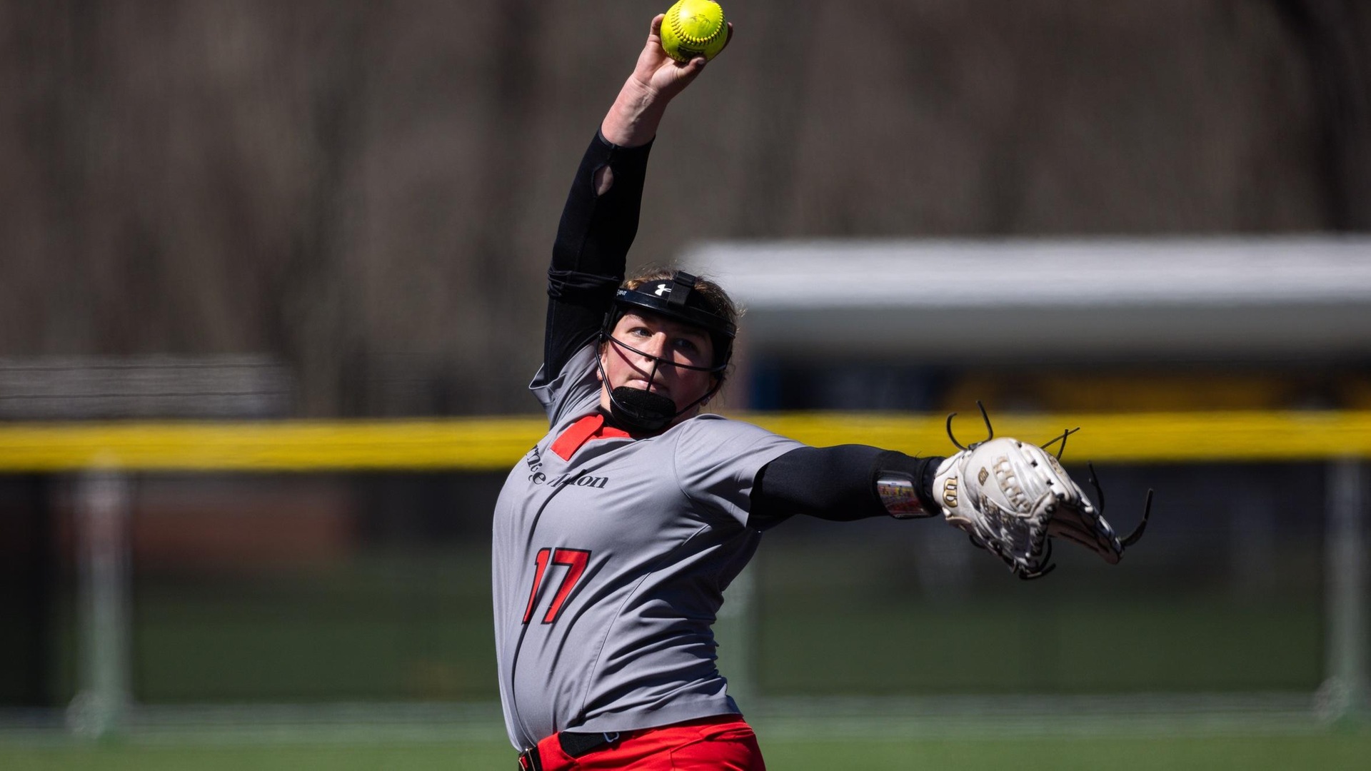 women's softball pitcher in motion with ball in hand above head