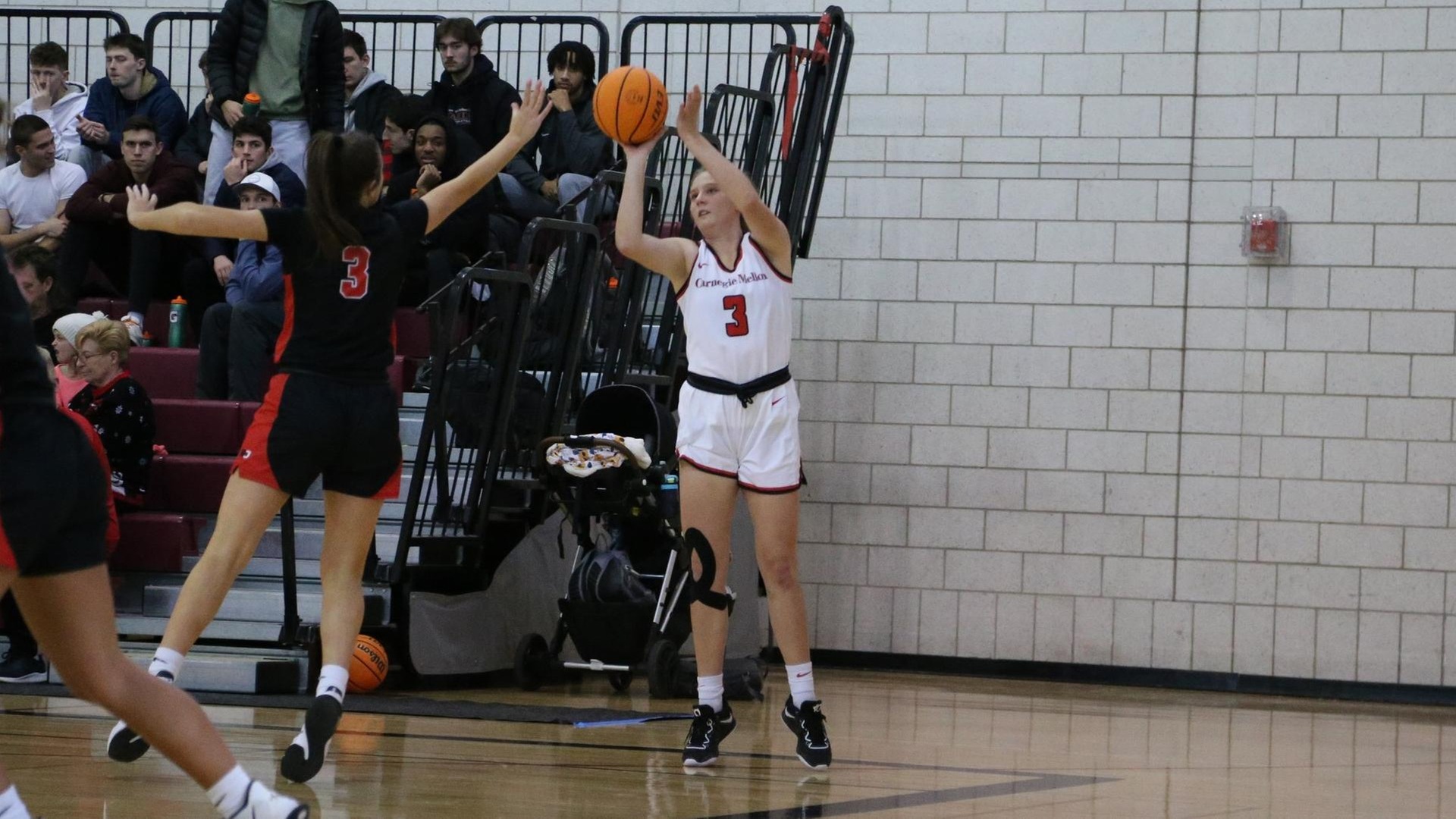 women's basketball player wearing a white uniform takes a shot from the corner of the court