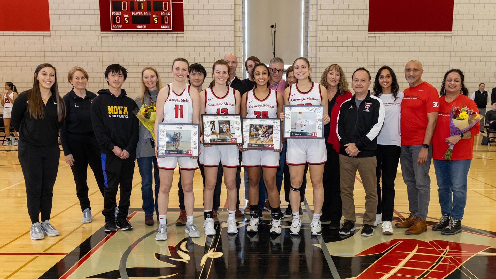 group of basketball players and family members standing together with the four players holding framed photos