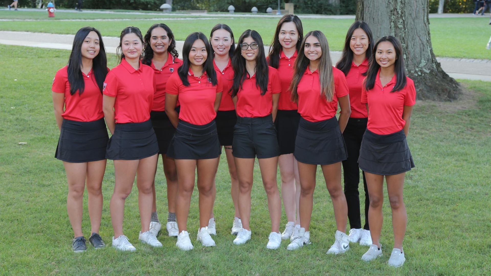 women's golf team photo with players wearing red shirts and black bottoms standing in two rows