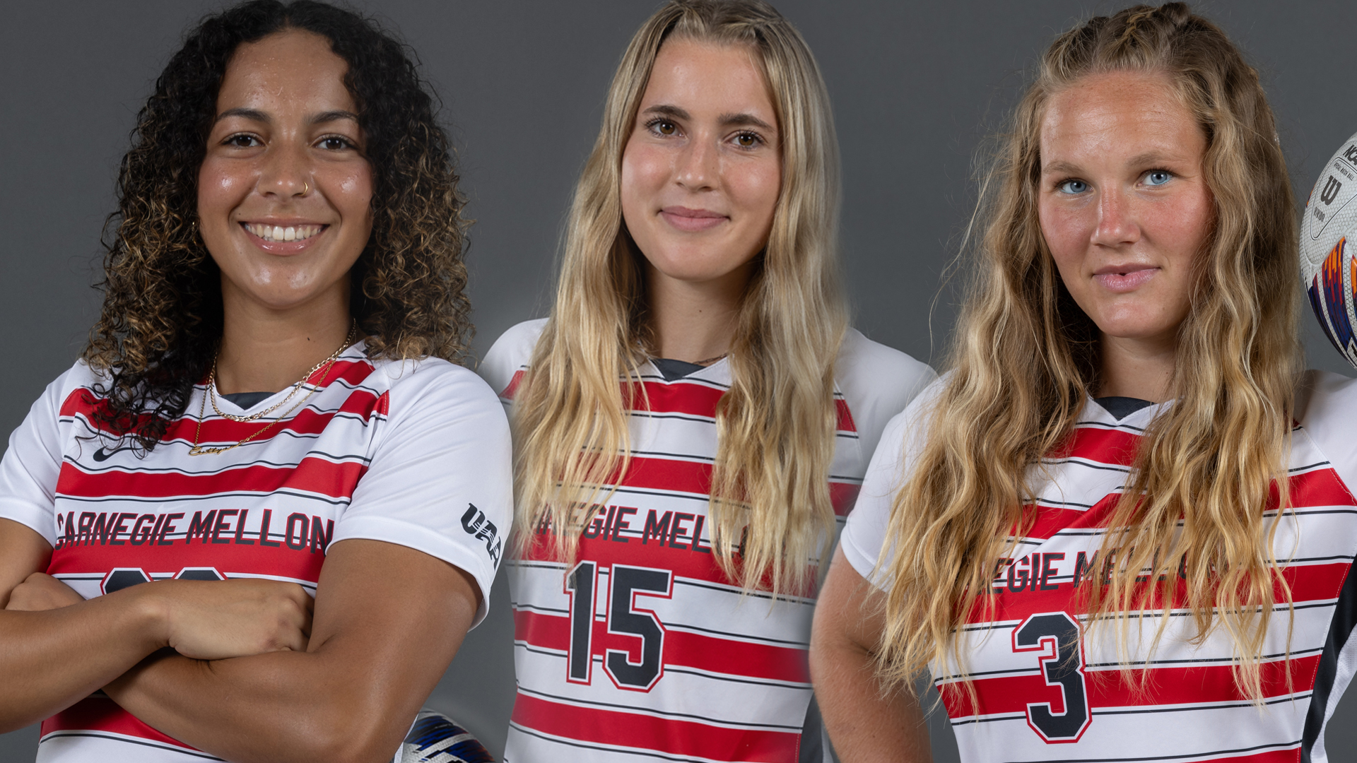 three women's soccer players wearing white and red striped jerseys pose with arms crossed or on hips