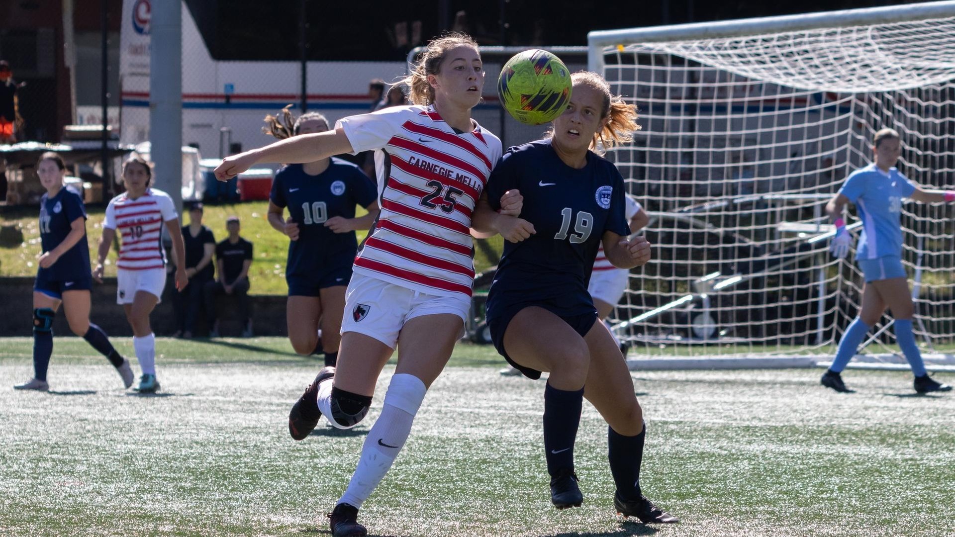 women's soccer player wearing a white uniform plays against a player wearing a blue uniform