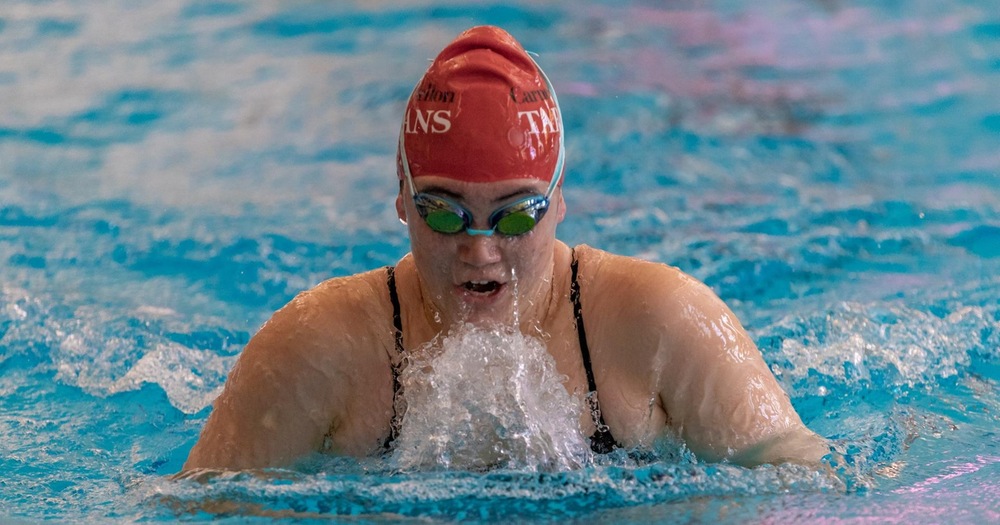 women's swimmer wearing red swim cap doing breaststroke