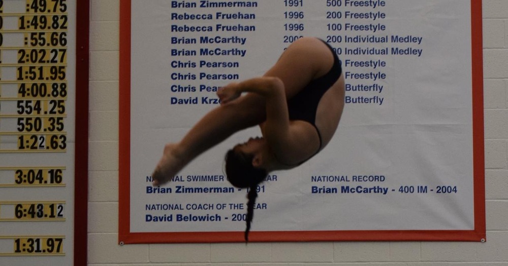women's diver in midair with hands tucked under straight legs