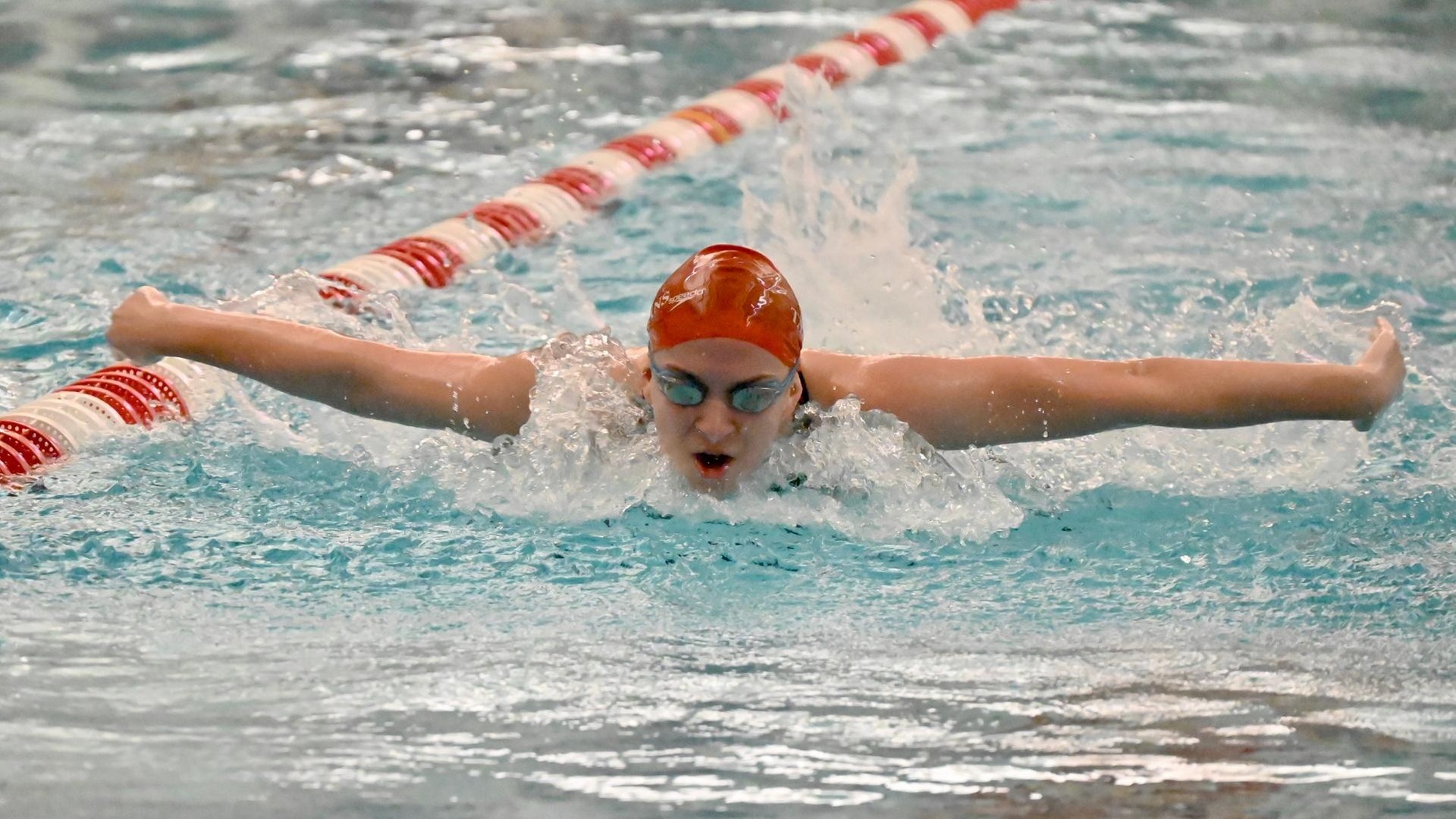 women's swimmer doing butterfly stroke with arms above water