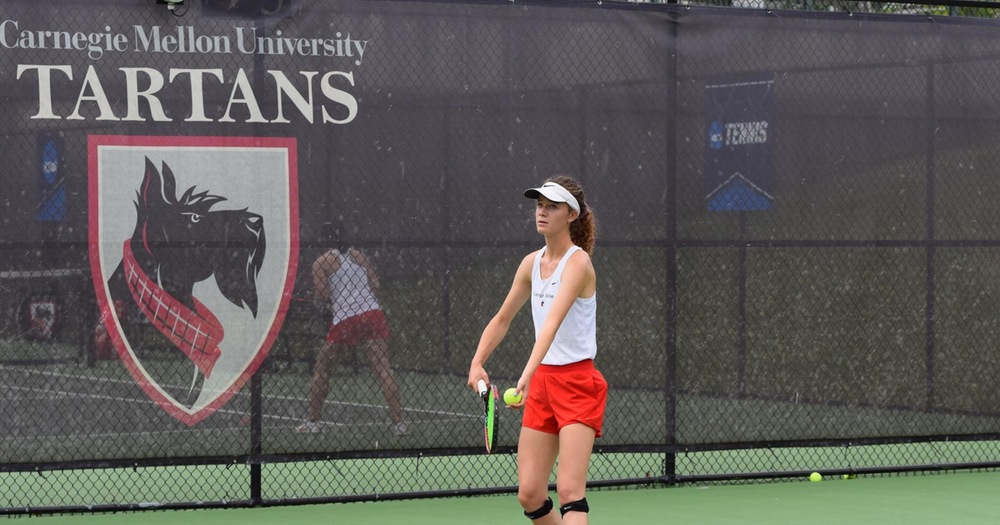 women's tennis player wearing white tank top and red shorts prepares to serve