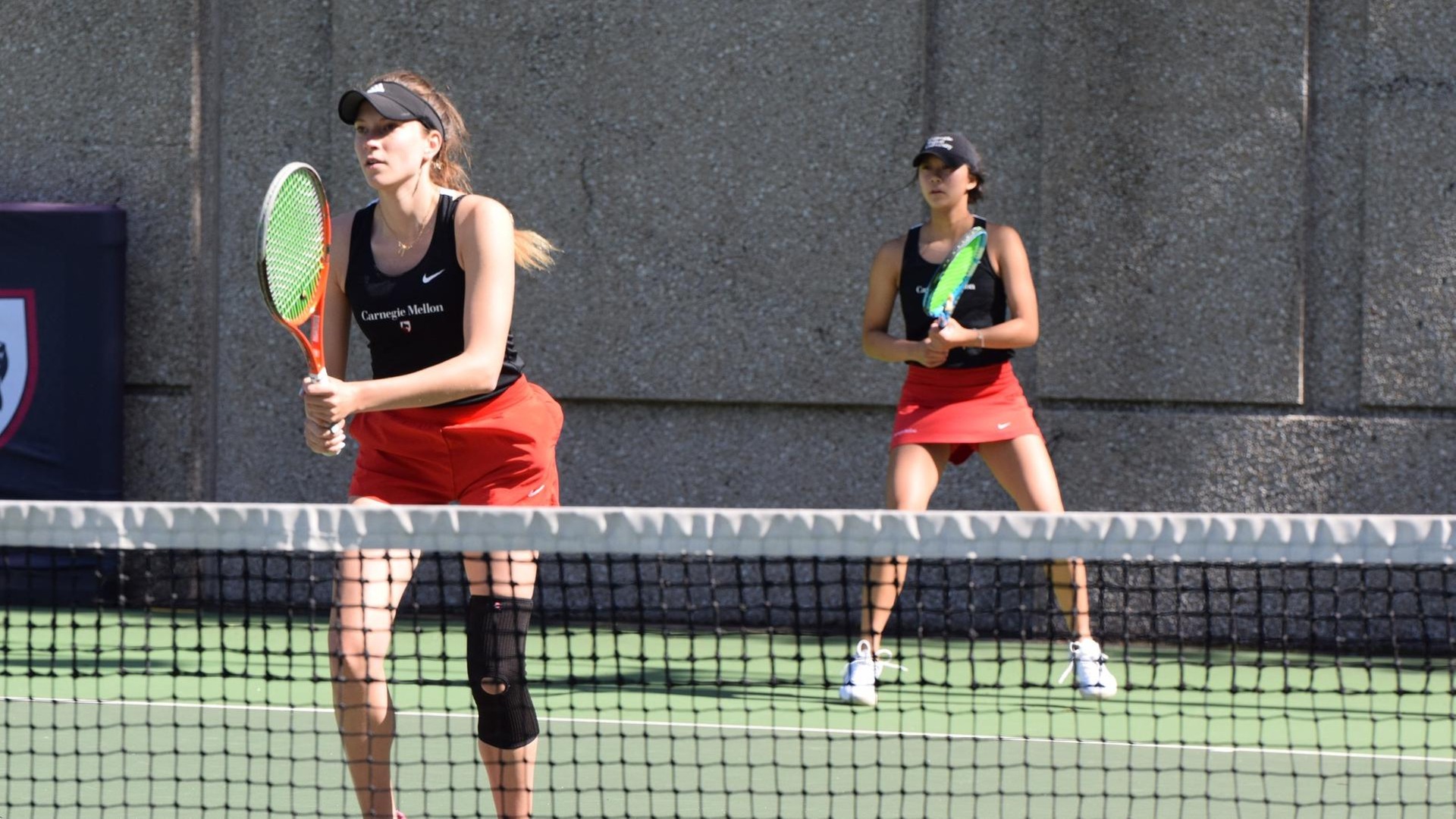 women's tennis doubles team with one player near net and second player at back line