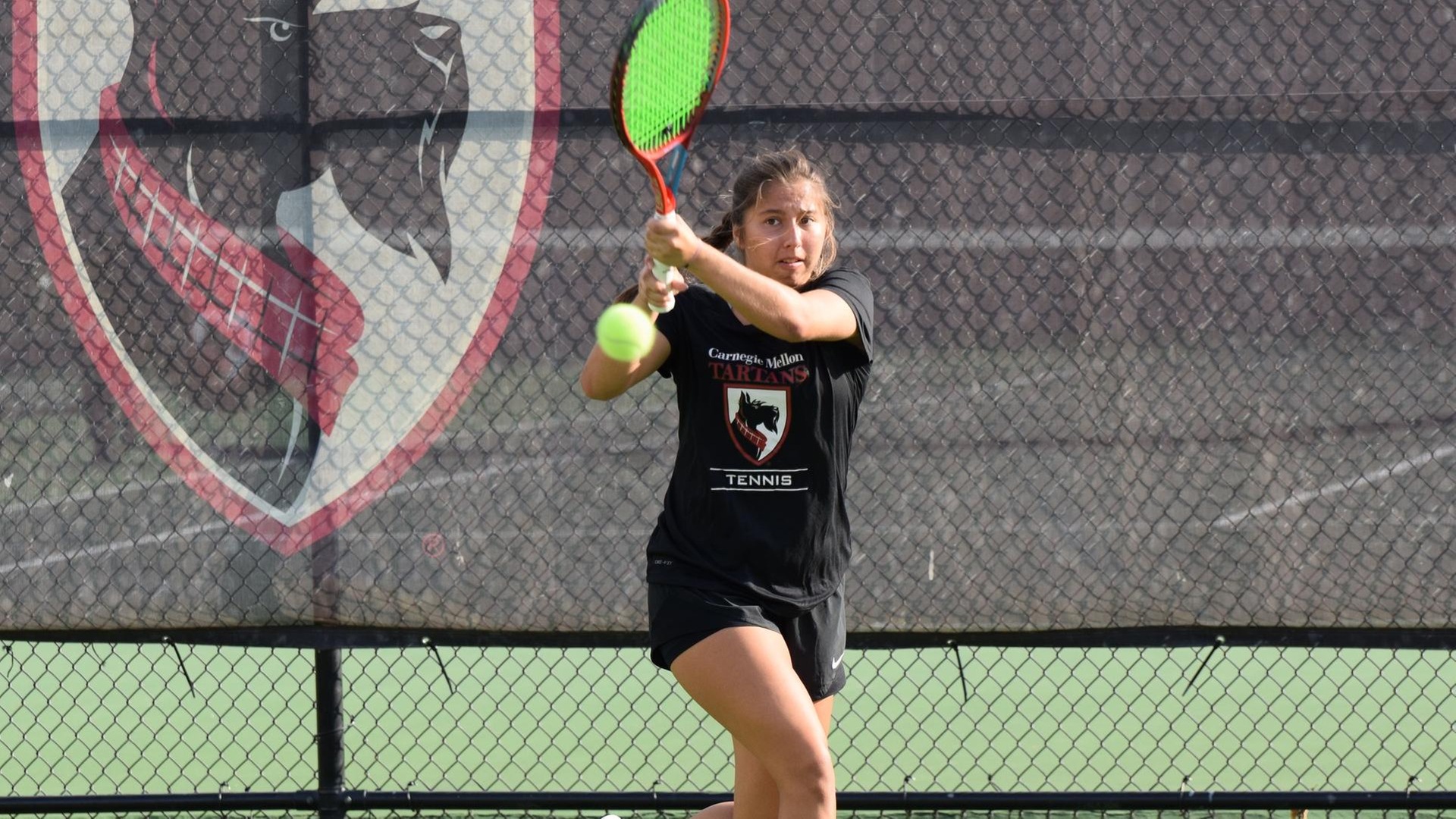 women's tennis player wearing a black shirt and black shorts swinging a racquet