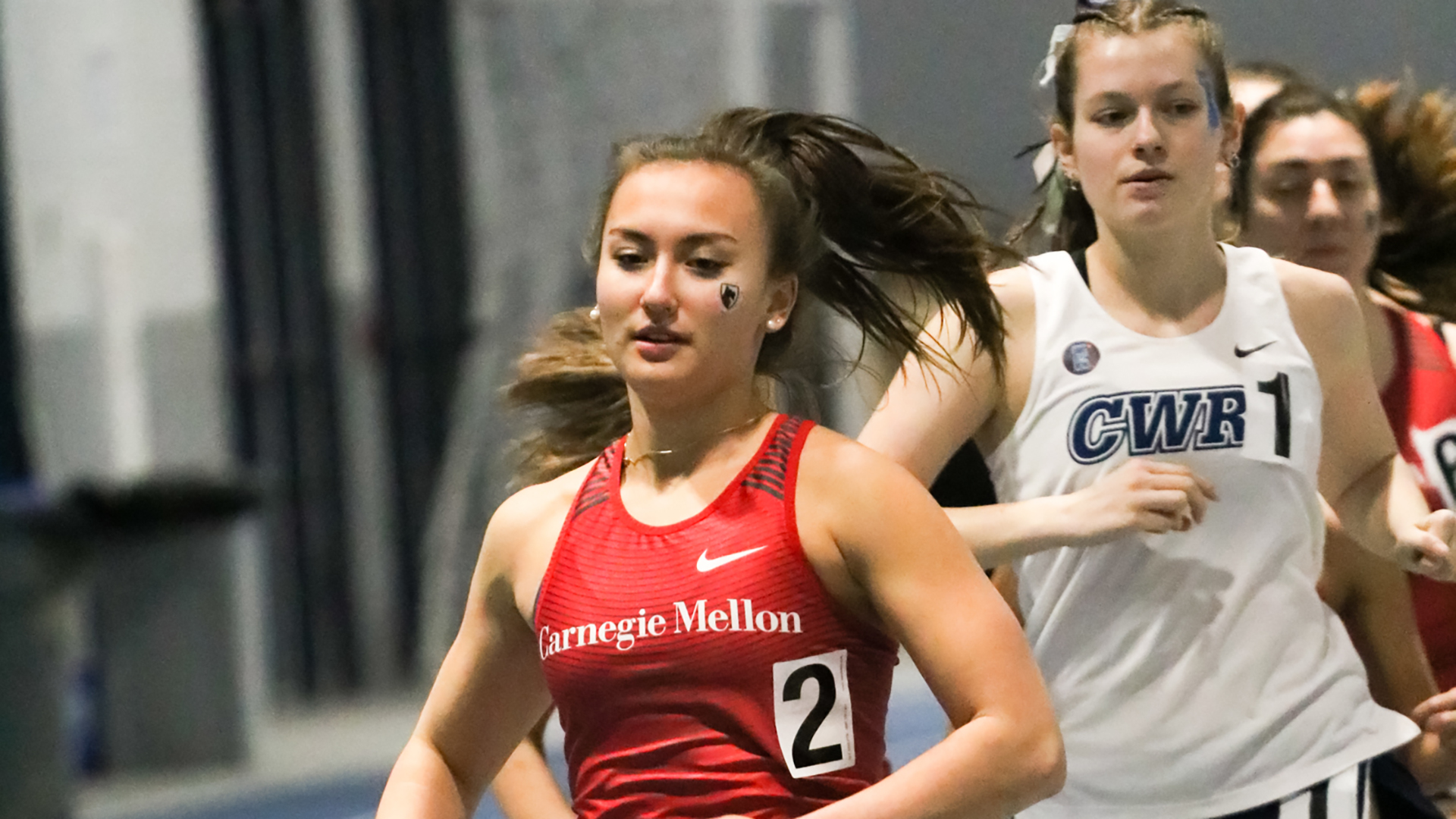 women's track runner wearing a red jersey top races in front of others