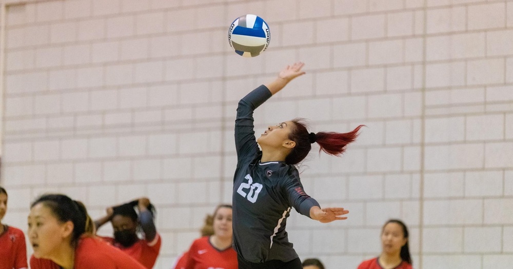 women's volleyball player wearing gray top serving the ball