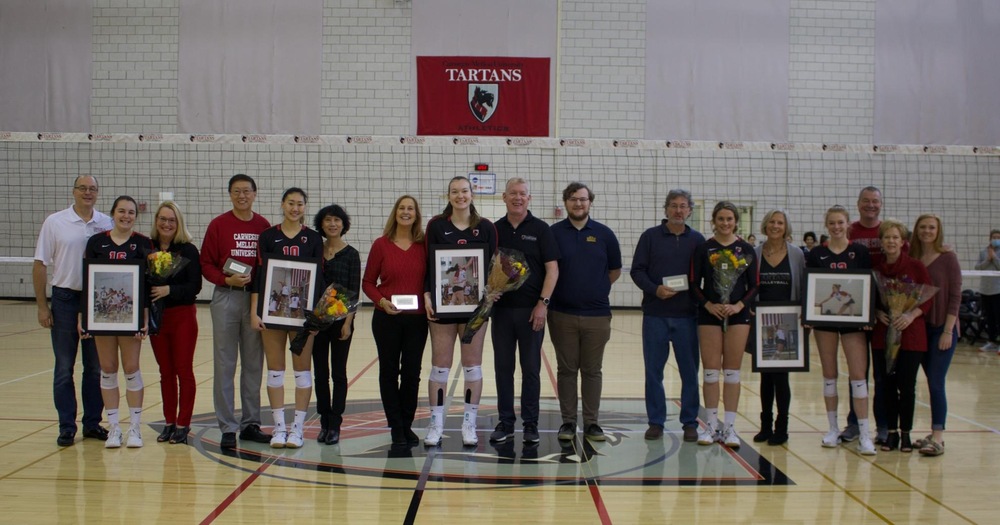 group of people standing together with large images and flowers for senior volleyball players