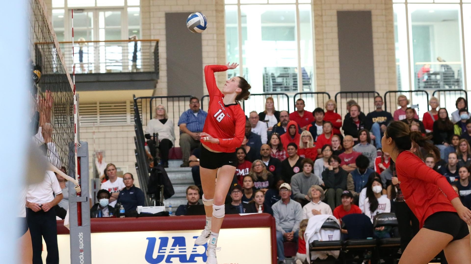 women's volleyball player jumping to hit the ball with her right hand