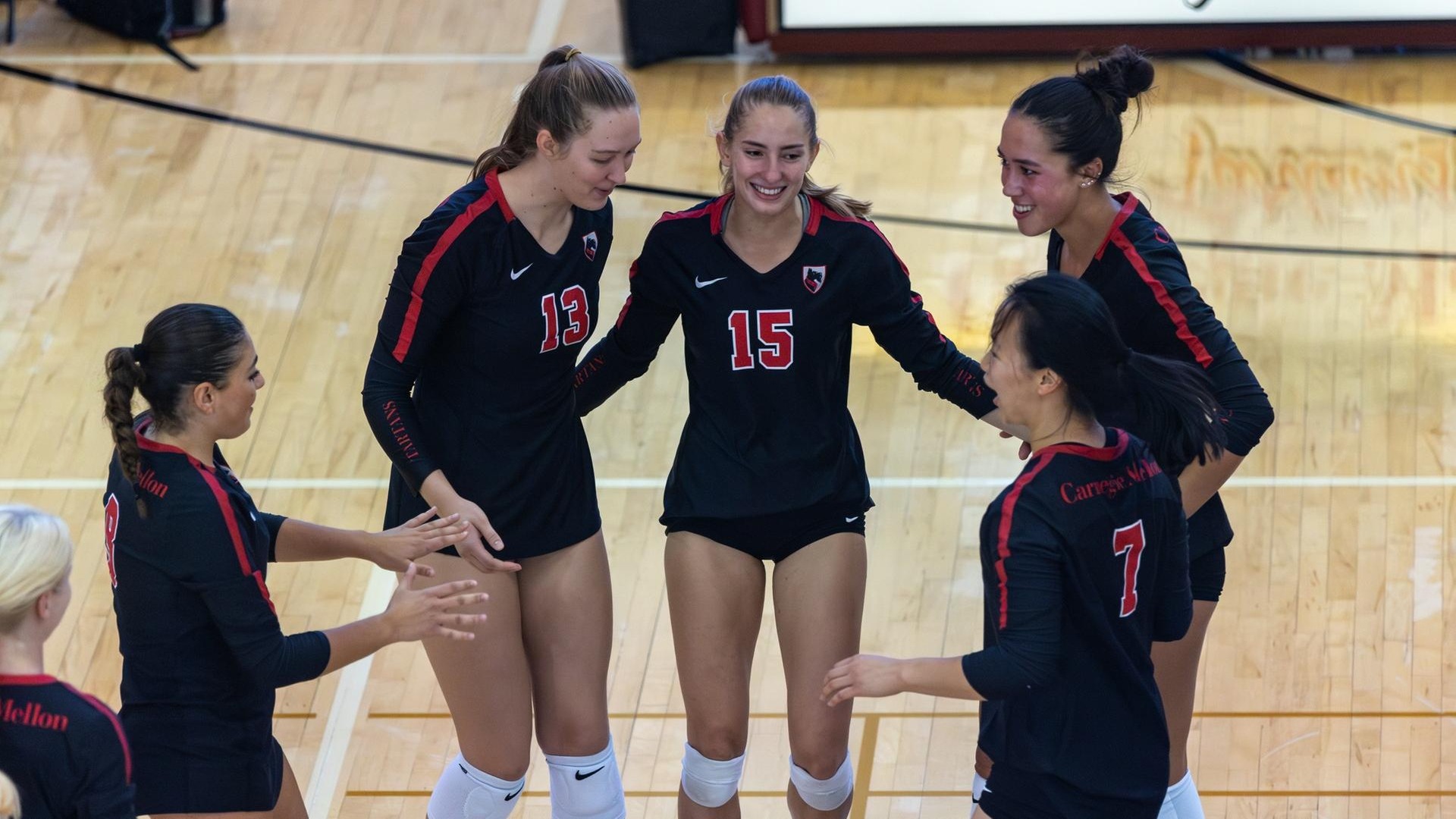 women's volleyball players coming together for a huddle