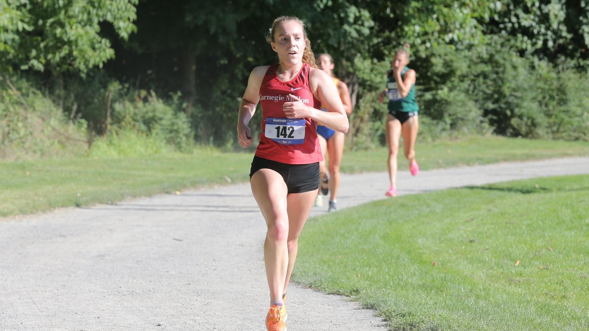 women's cross country runner wearing red tank top and black shorts on a trail