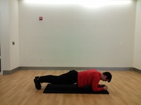 side view of man in plank position with forearms touching floor