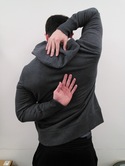 back view of person with right hand touching back of neck and left hand touching middle of back