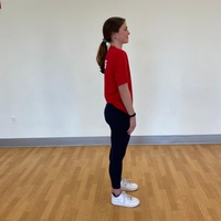 side profile of person standing straight with arms at side with shoulders rotating forward